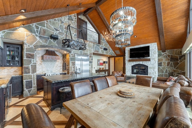 dining area featuring wood ceiling, a notable chandelier, high vaulted ceiling, a fireplace, and beam ceiling