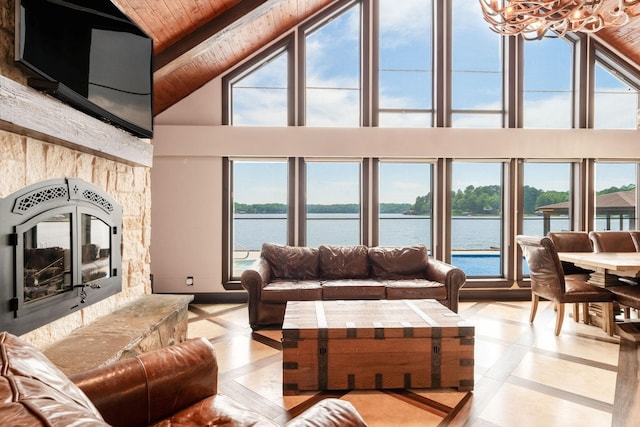 tiled living room with beam ceiling, wood ceiling, a water view, and a stone fireplace