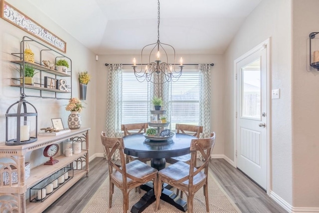 dining area with a chandelier, lofted ceiling, and wood-type flooring