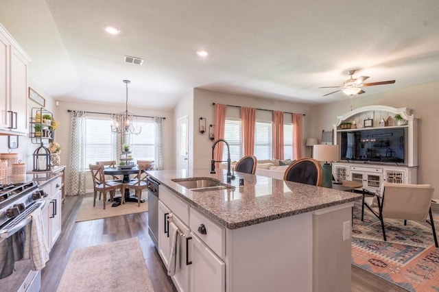 kitchen featuring an island with sink, stainless steel appliances, white cabinets, light stone counters, and sink