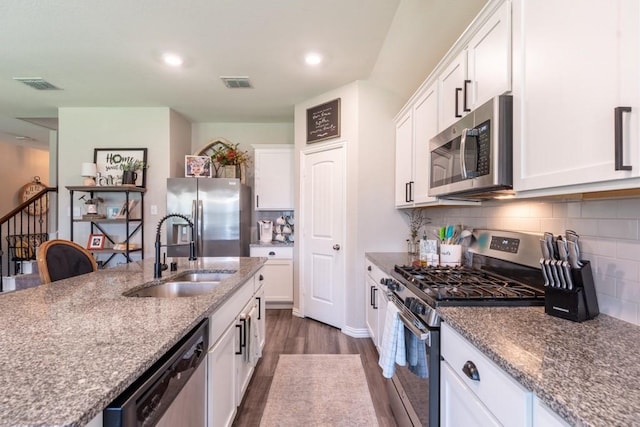 kitchen with white cabinetry, stainless steel appliances, dark hardwood / wood-style floors, light stone countertops, and sink