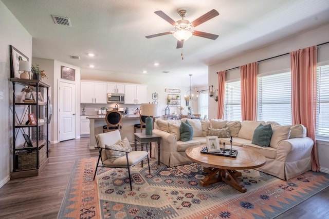 living room with dark wood-type flooring and ceiling fan with notable chandelier