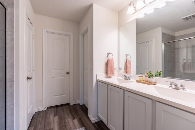 bathroom with walk in shower, vanity, and hardwood / wood-style flooring