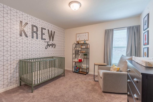 bedroom with light colored carpet and a nursery area