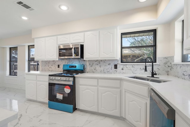 kitchen featuring appliances with stainless steel finishes, tasteful backsplash, white cabinets, and sink