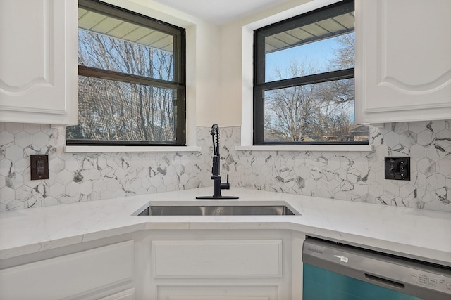 kitchen featuring white cabinets, light stone countertops, dishwasher, and sink