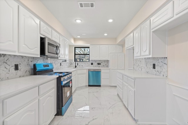 kitchen featuring appliances with stainless steel finishes, white cabinets, and sink