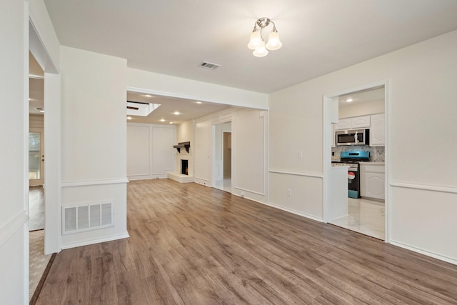 unfurnished living room with a brick fireplace and light hardwood / wood-style flooring