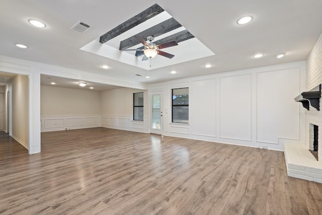 unfurnished living room with ceiling fan, light hardwood / wood-style flooring, and a brick fireplace