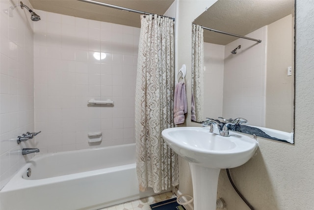 bathroom featuring shower / bathtub combination with curtain, sink, and a textured ceiling