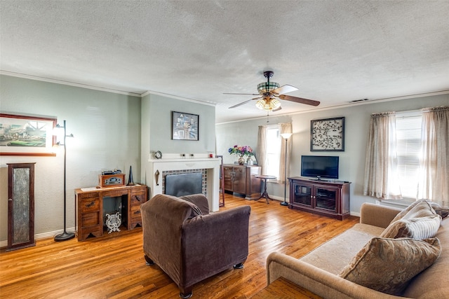 living room with a fireplace, a wealth of natural light, a textured ceiling, and light wood-type flooring