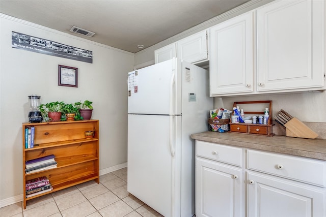 kitchen with white cabinetry, light tile patterned flooring, and white fridge