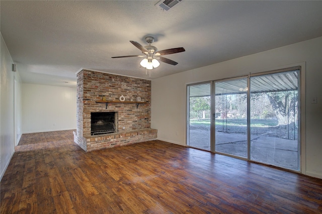 unfurnished living room featuring a fireplace, a textured ceiling, ceiling fan, and dark hardwood / wood-style floors