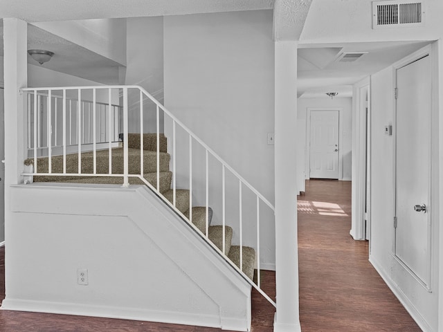 stairway featuring a textured ceiling and wood-type flooring