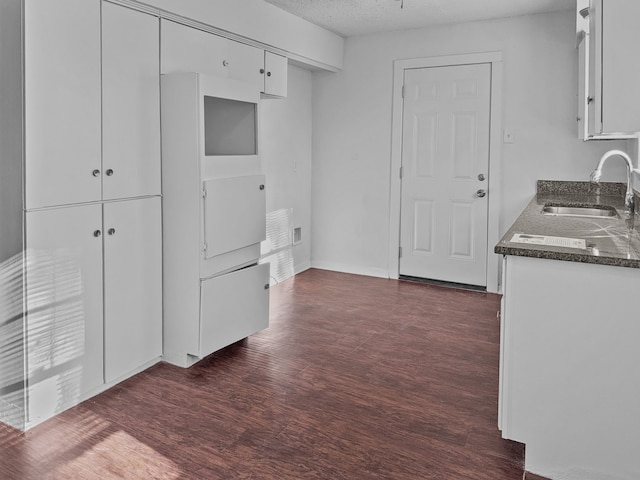 kitchen with a textured ceiling, white cabinetry, dark hardwood / wood-style floors, and sink