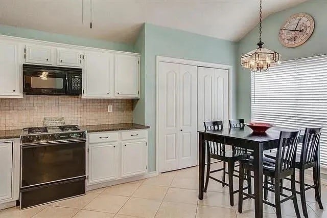 kitchen featuring white cabinets, tasteful backsplash, hanging light fixtures, gas range, and light tile patterned floors