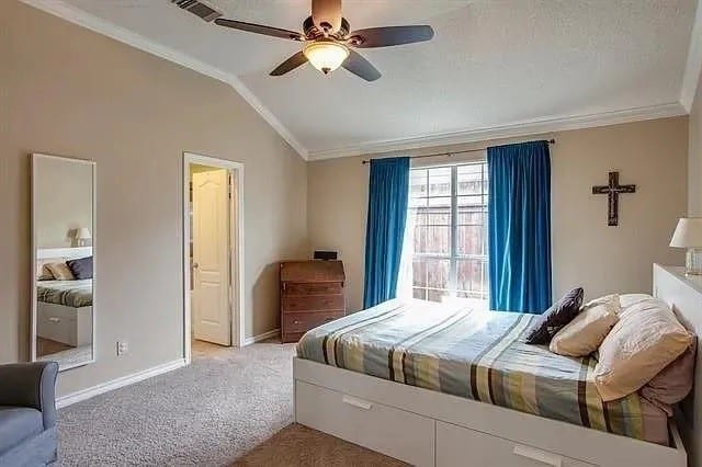 bedroom featuring ceiling fan, light colored carpet, vaulted ceiling, and ornamental molding