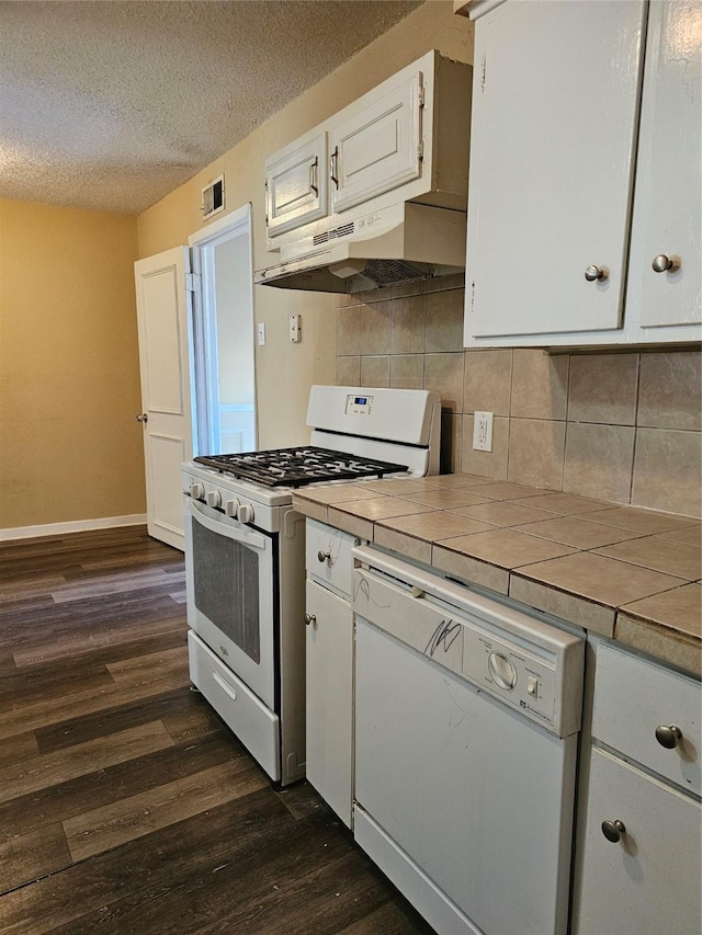 kitchen featuring white appliances, dark hardwood / wood-style flooring, tile countertops, white cabinets, and tasteful backsplash