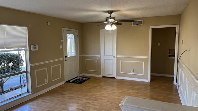 entrance foyer with a textured ceiling, ceiling fan, and light wood-type flooring