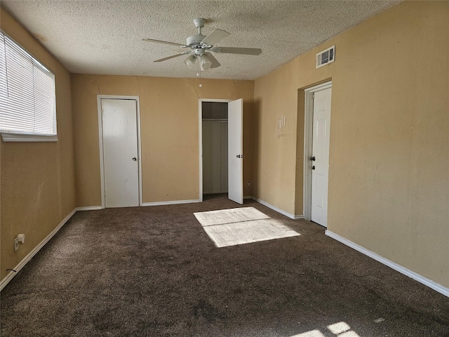 unfurnished bedroom featuring a textured ceiling, ceiling fan, and dark carpet