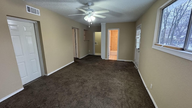 unfurnished bedroom with connected bathroom, a textured ceiling, ceiling fan, and dark colored carpet