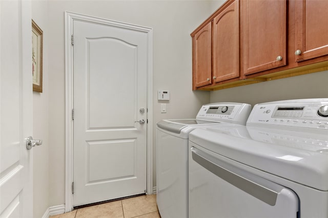 laundry area featuring separate washer and dryer, cabinets, and light tile patterned floors