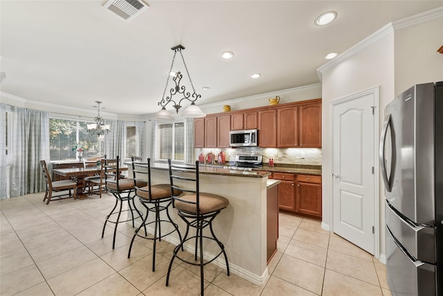 kitchen featuring pendant lighting, a center island, stainless steel appliances, light tile patterned floors, and crown molding