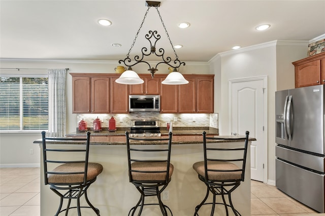 kitchen with decorative light fixtures, a kitchen island, a breakfast bar area, appliances with stainless steel finishes, and light tile patterned flooring