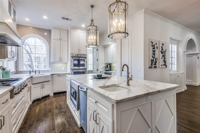 kitchen featuring a center island with sink, appliances with stainless steel finishes, pendant lighting, and sink