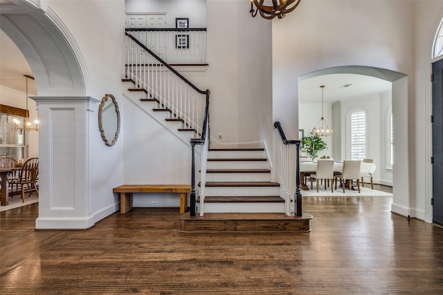 foyer with dark wood-type flooring, an inviting chandelier, and a towering ceiling