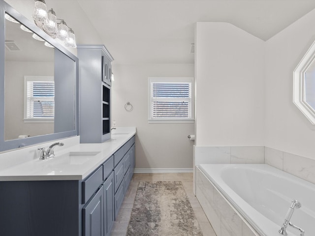 bathroom with tile patterned flooring, vanity, a healthy amount of sunlight, and tiled bath