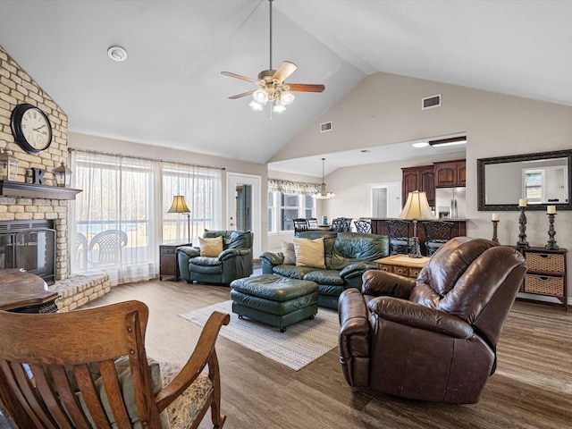 living room with hardwood / wood-style flooring, vaulted ceiling, ceiling fan, and a fireplace