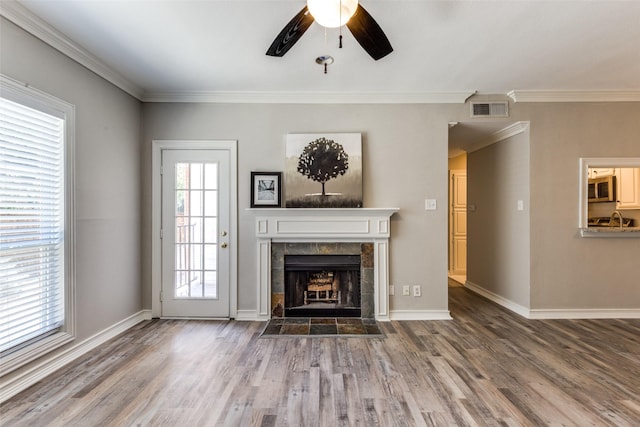 unfurnished living room featuring hardwood / wood-style flooring, ceiling fan, a tile fireplace, and ornamental molding