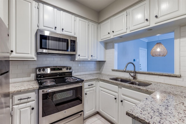 kitchen featuring appliances with stainless steel finishes, pendant lighting, decorative backsplash, white cabinets, and sink