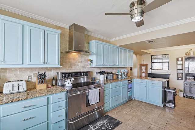 kitchen with range with two ovens, kitchen peninsula, blue cabinets, and wall chimney range hood