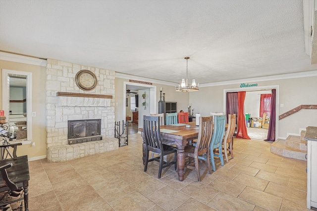 dining area with a textured ceiling, ornamental molding, a stone fireplace, and a notable chandelier