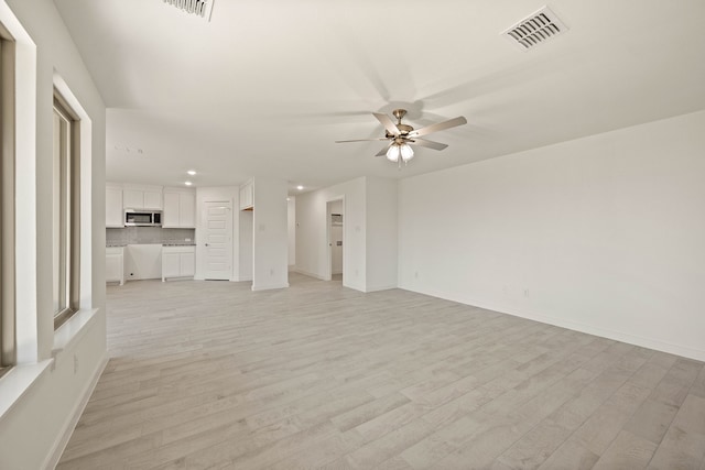 unfurnished living room featuring ceiling fan and light wood-type flooring