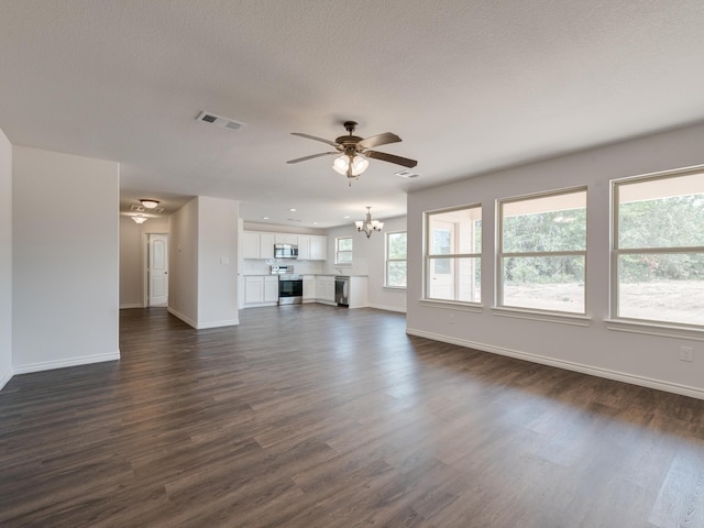 unfurnished living room with ceiling fan with notable chandelier, dark wood-type flooring, and a wealth of natural light