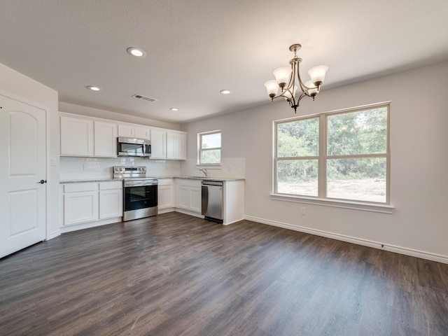 kitchen featuring appliances with stainless steel finishes, white cabinetry, a wealth of natural light, and hanging light fixtures