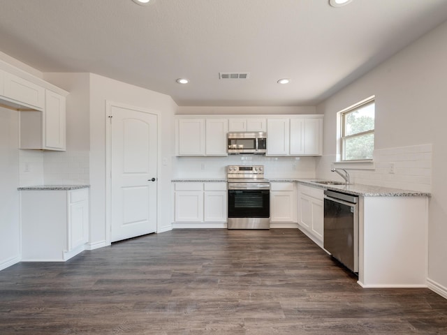 kitchen featuring stainless steel appliances, white cabinetry, dark hardwood / wood-style flooring, and light stone countertops