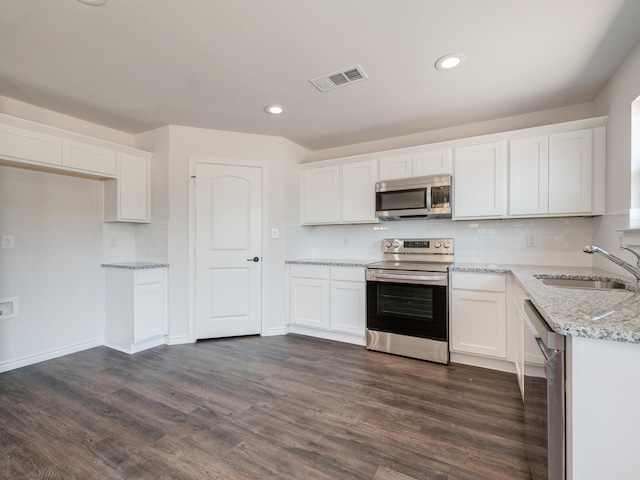 kitchen featuring dark wood-type flooring, light stone countertops, stainless steel appliances, white cabinets, and sink