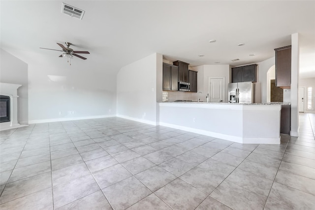 kitchen featuring kitchen peninsula, stainless steel appliances, light tile patterned floors, ceiling fan, and dark brown cabinets