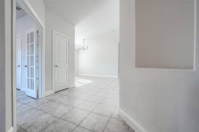 hallway with light tile patterned flooring and a chandelier