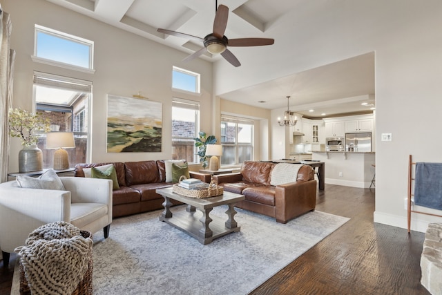 living room with ceiling fan with notable chandelier, a high ceiling, and dark hardwood / wood-style flooring