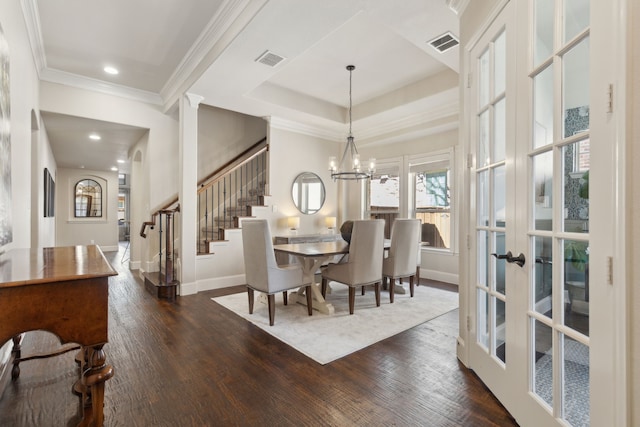 dining space featuring an inviting chandelier, a raised ceiling, dark wood-type flooring, french doors, and crown molding