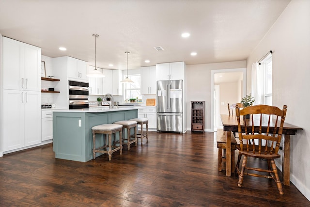 kitchen with white cabinetry, an island with sink, a breakfast bar area, pendant lighting, and appliances with stainless steel finishes