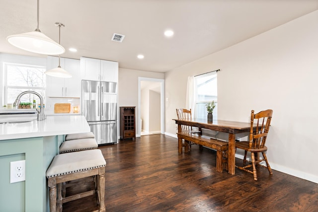 kitchen with white cabinets, stainless steel fridge, dark wood-type flooring, sink, and decorative light fixtures