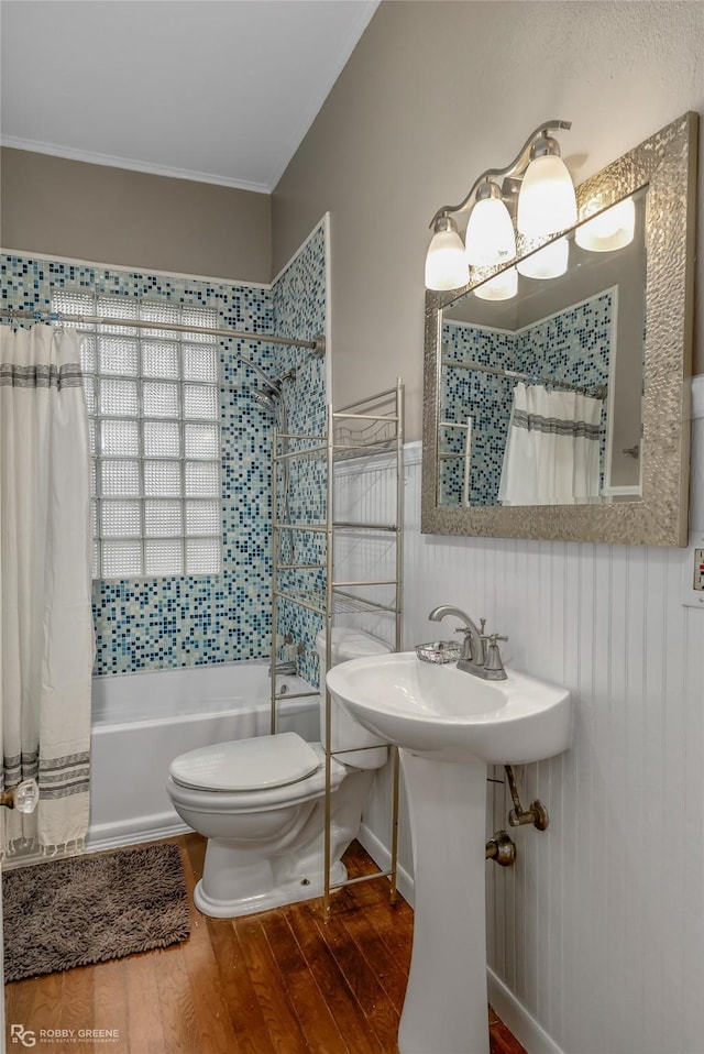 bathroom with ornamental molding, hardwood / wood-style floors, shower / bath combination with curtain, and toilet