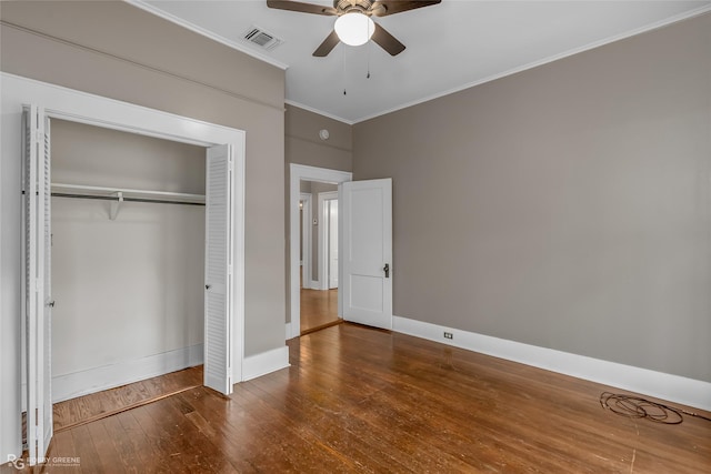 unfurnished bedroom with ceiling fan, dark wood-type flooring, ornamental molding, and a closet