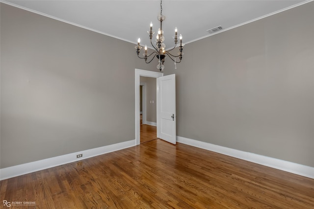 empty room with hardwood / wood-style floors, a chandelier, and ornamental molding